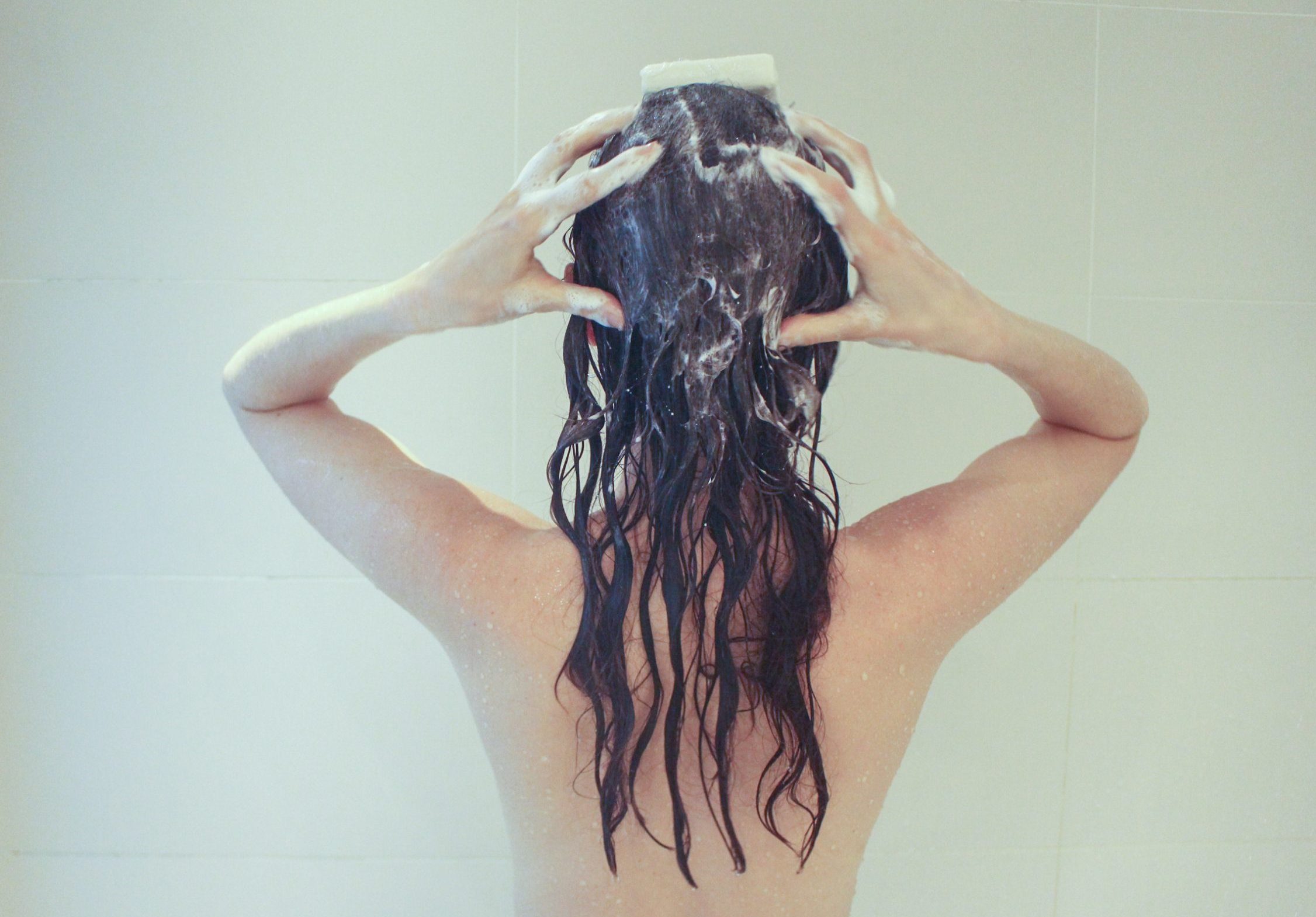 girl washing hair with shampoo bar in a plastic free bathroom